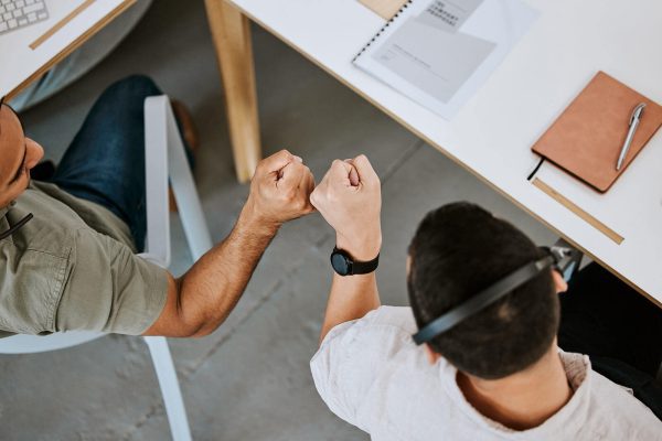 Deux hommes assis à une table, se font un check